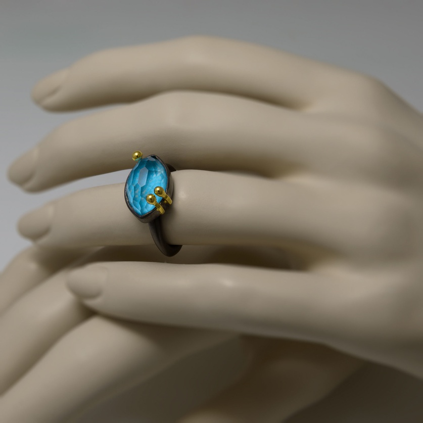 Oval-shaped silver ring with gold and turquoise doublet stone