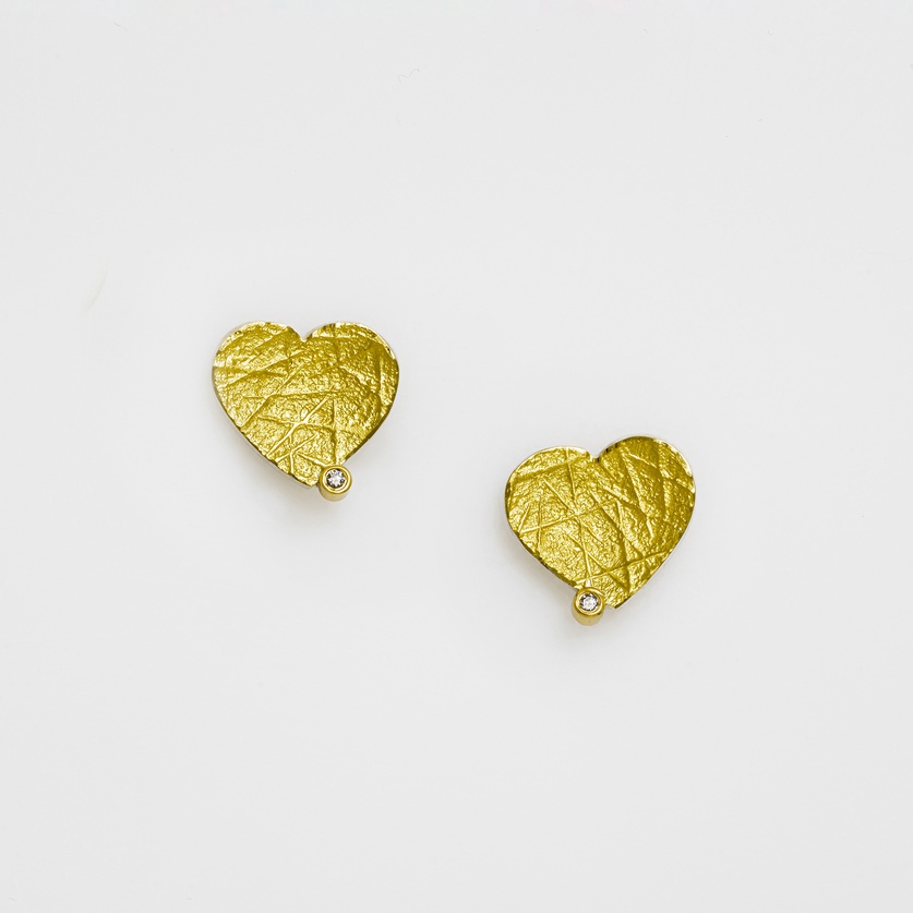 Heart shaped stud earrings in silver and gold with small diamonds